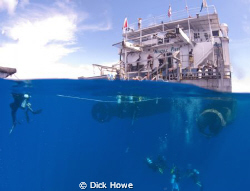 Split of diving boat with divers on ladder and approachin... by Dick Howe 